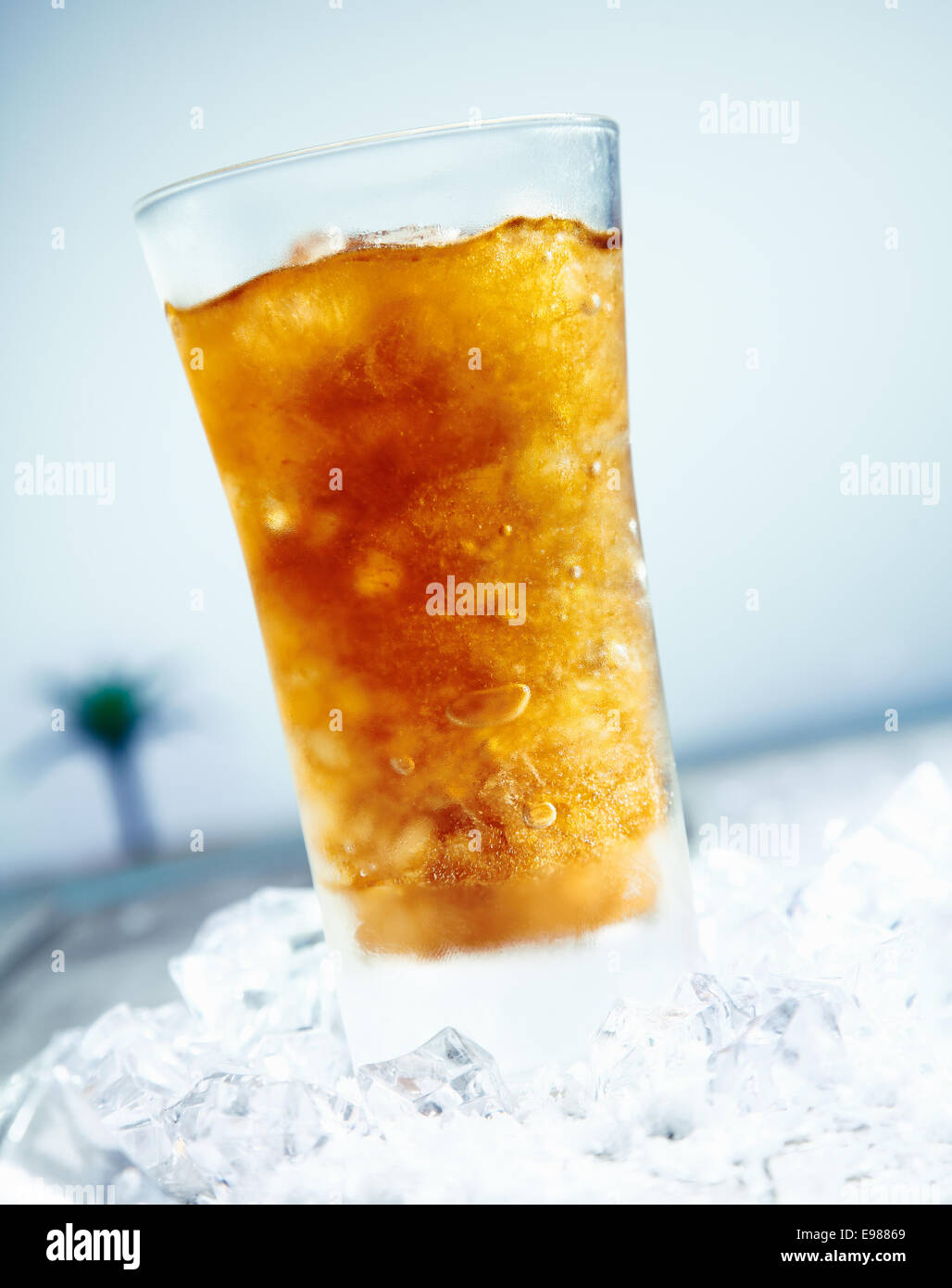 Eisgekühlte Cola vor dem Strand. Mit Eiswürfel und eine Palme im Hintergrund. Stockfoto