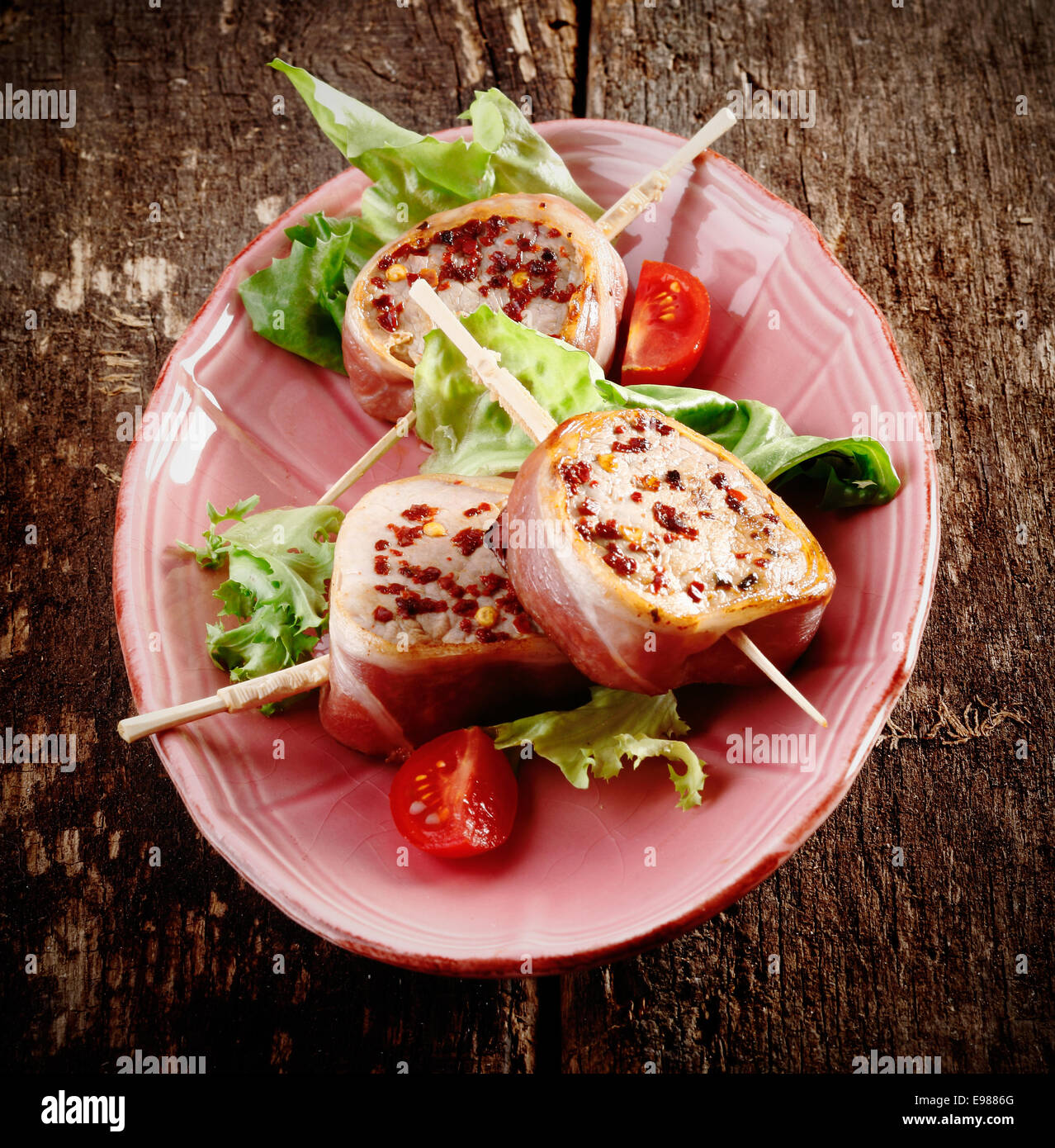 Rustikale Schweinsfilet mit Salat serviert eine Tomate auf einer alten Holzbrett Stockfoto