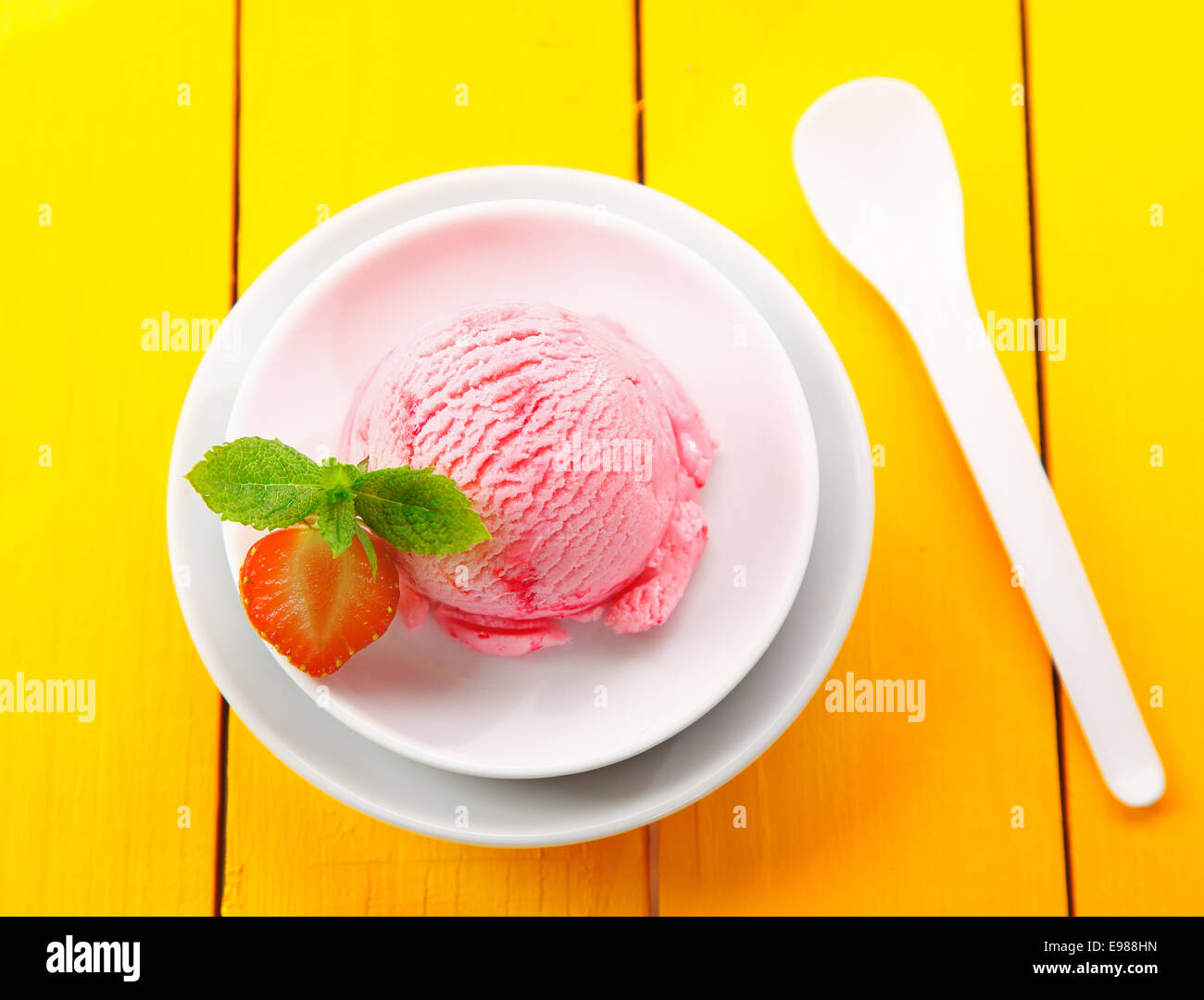 Draufsicht einer runden Kugel Portion cremige Erdbeer Eis in einer runden Schüssel auf gelbe Tisch serviert Stockfoto