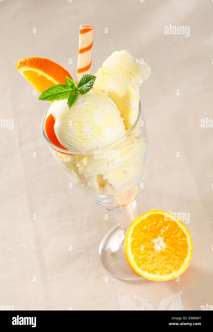 Bunten tropischen Eis Dessert mit frischen Orangenscheiben und eine Spirale Wafer Keks Stockfoto