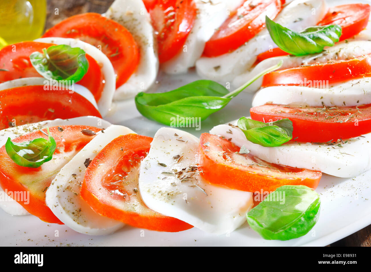 Kunstvoll arrangiert und Tomaten Salat in wechselnden Scheiben von roten und weißen garniert mit frischen Kräutern Stockfoto