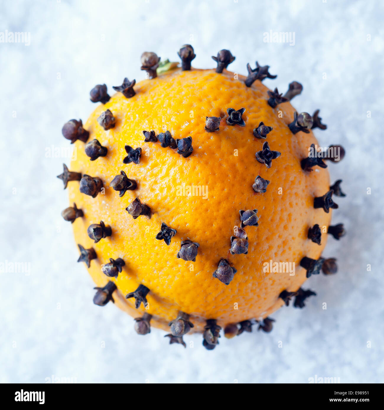 Weihnachts-Dekoration frische ganze Orange mit einer würzigen Nelken Herz Dekoration Durchstechen der Haut liegend auf einem Bett aus Schnee Stockfoto