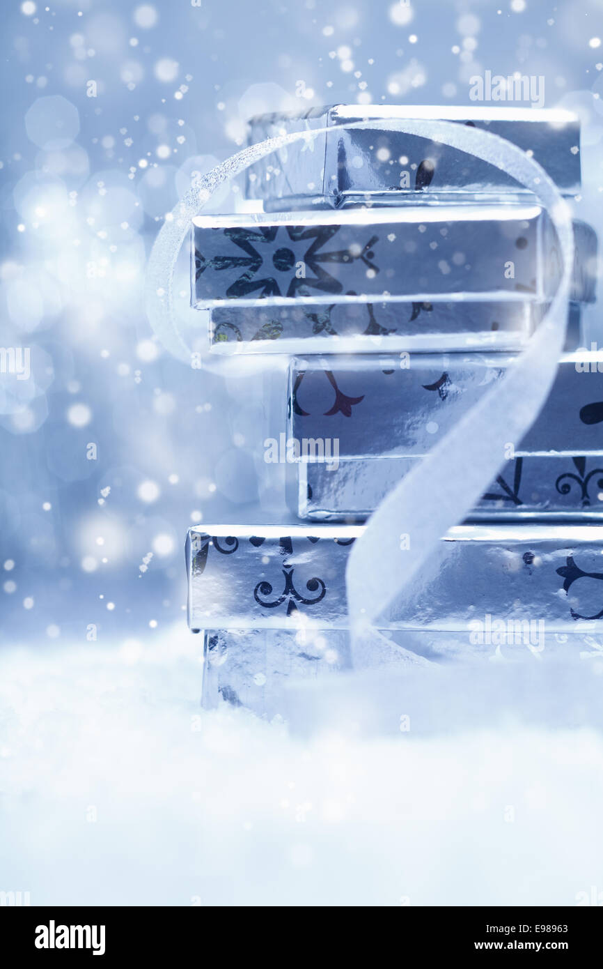 Ätherisch festlichen Hintergrund mit einem Stack von Silber Weihnachten Geschenk-Boxen mit einer dekorativen Schleife in fallenden Schnee Stockfoto