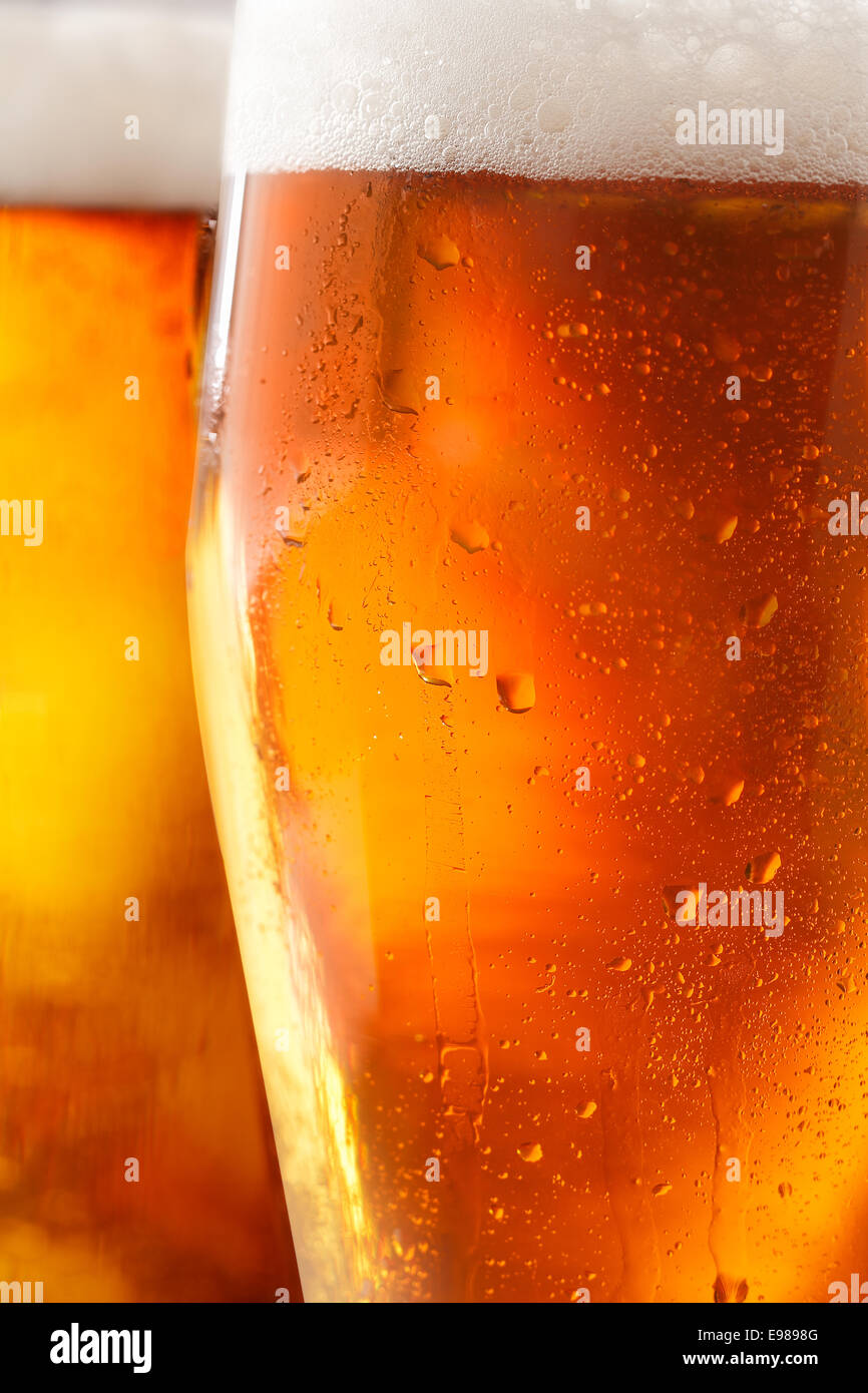 Zugeschnittenen Nahaufnahme von einem Glas kaltes Bier mit einer schaumigen Kopf und Wasser Tropfen Verflüssigungswärme Bördeln der Außenseite des Glases Stockfoto