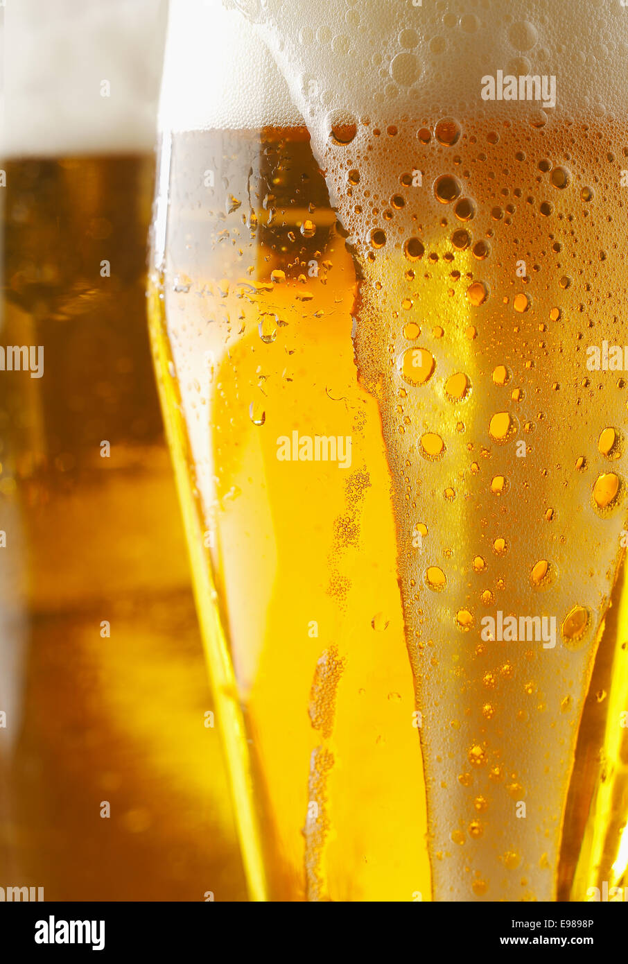 Nahaufnahme von einem schaumigen Cverflowing Glas golden Ale oder Bier mit Flüssigkeit laufen über die Außenseite des Glases, abgeschnitten Bild anzeigen Stockfoto
