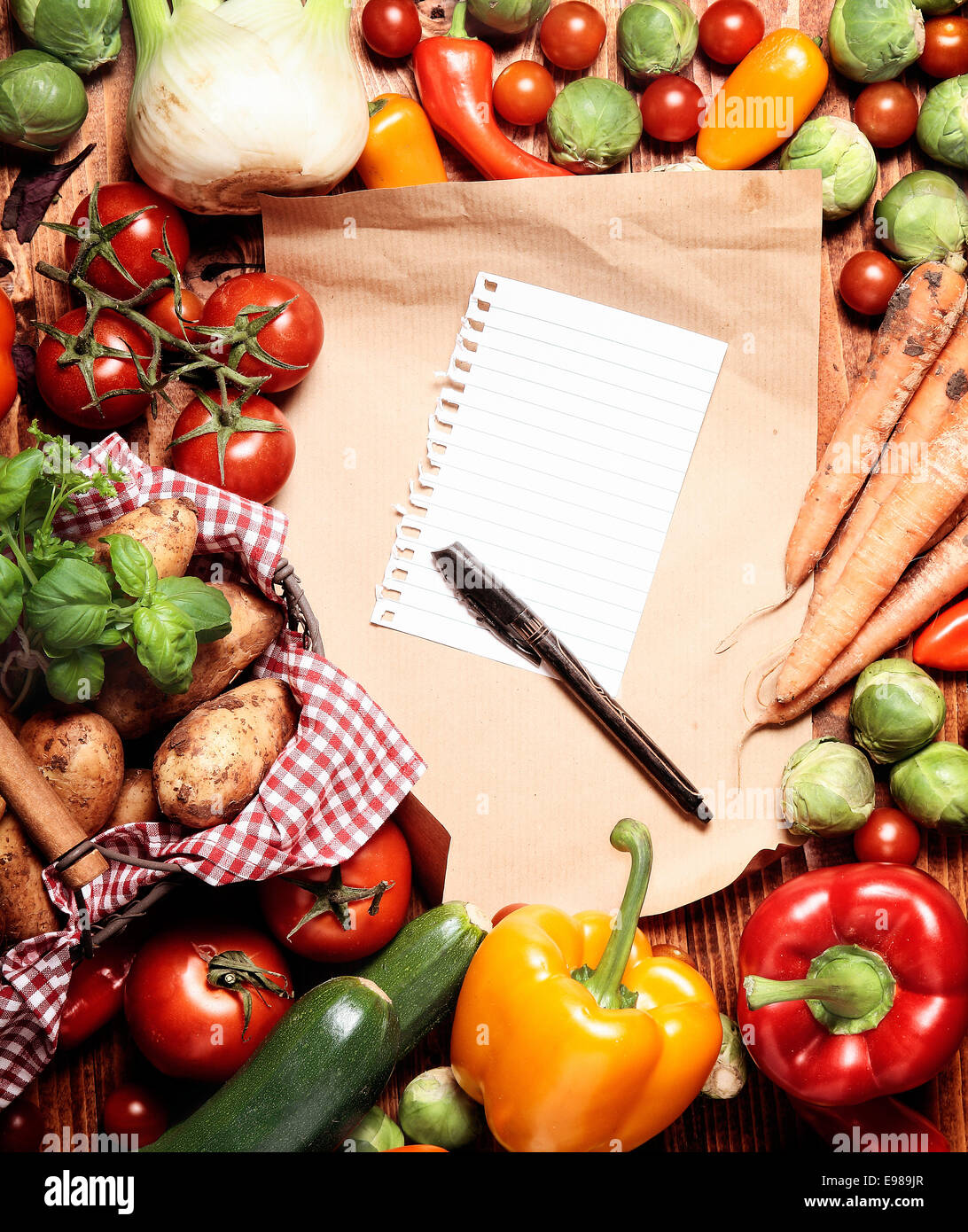 Einkaufsliste und Stift, umgeben von einer Variation von Gemüse Stockfoto