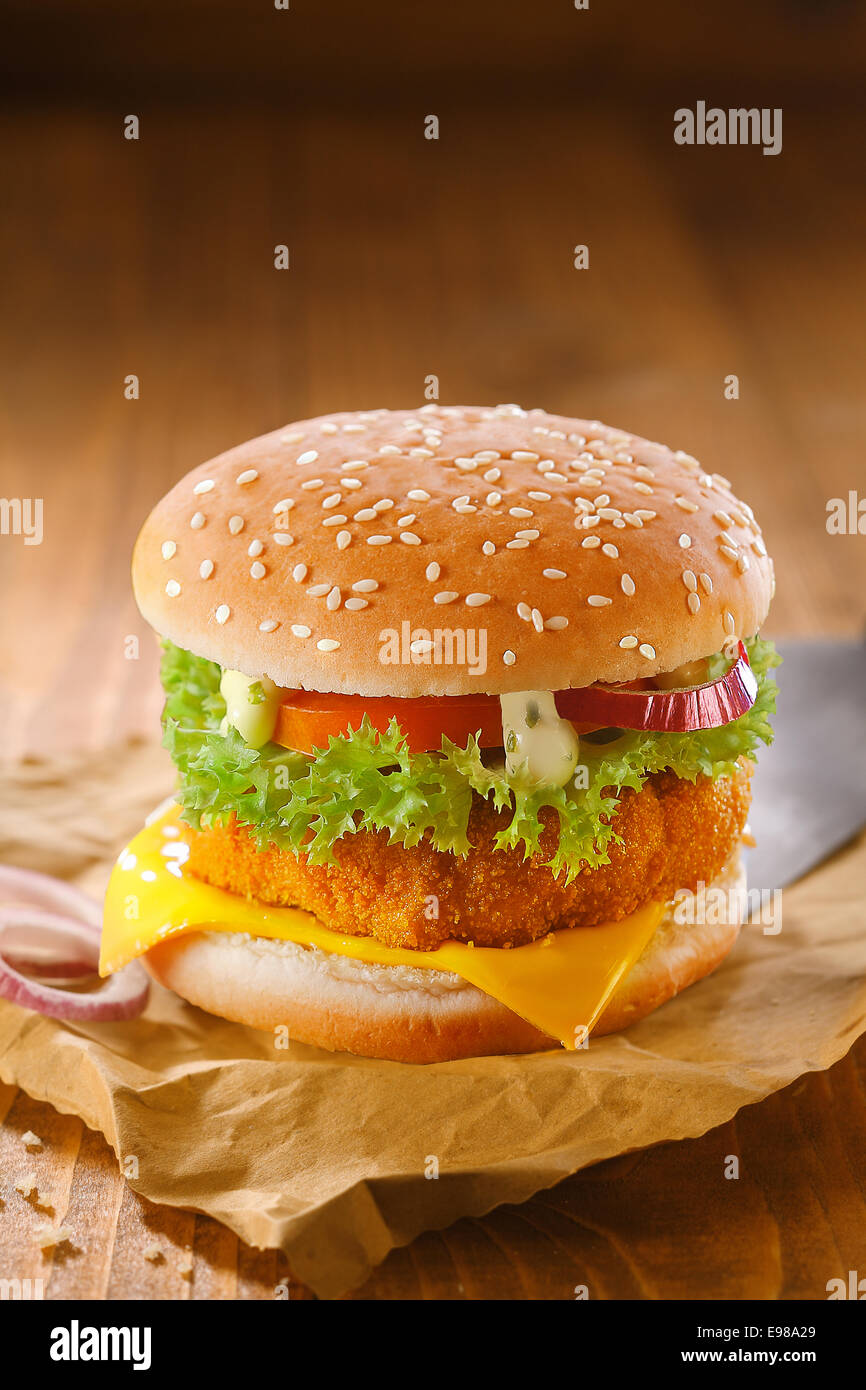 Leckere Hähnchen Burger mit einer goldenen Panierter Patty und Salat Zutaten auf trashigen zerknitterten braunem Papier aus Holz im Hintergrund mit Exemplar Stockfoto