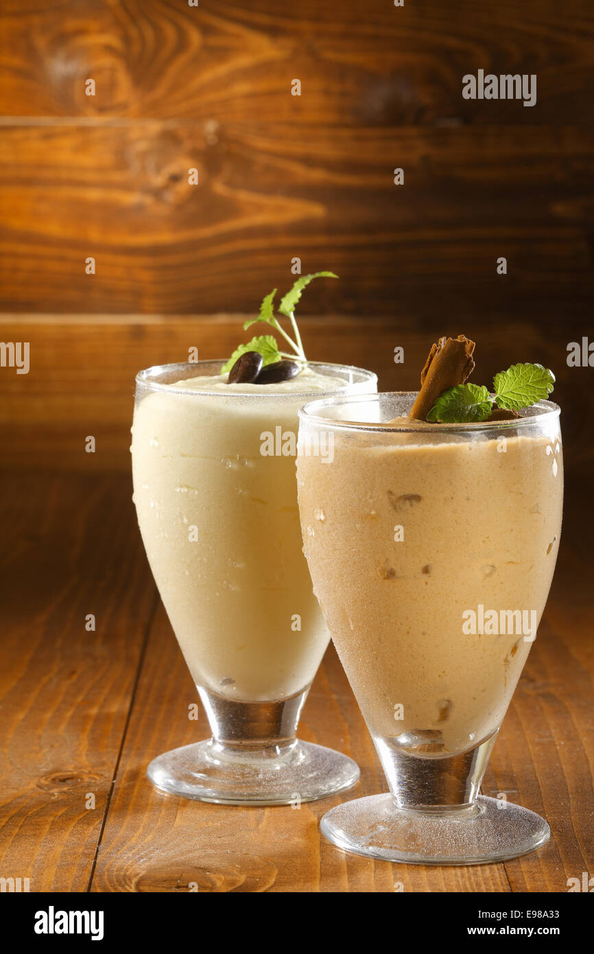 Cremige Dicke Milchshakes oder Pudding Dessert in gekühlte Gläser mit Schokolade garniert und serviert auf einem hölzernen Hintergrund mit Exemplar Stockfoto