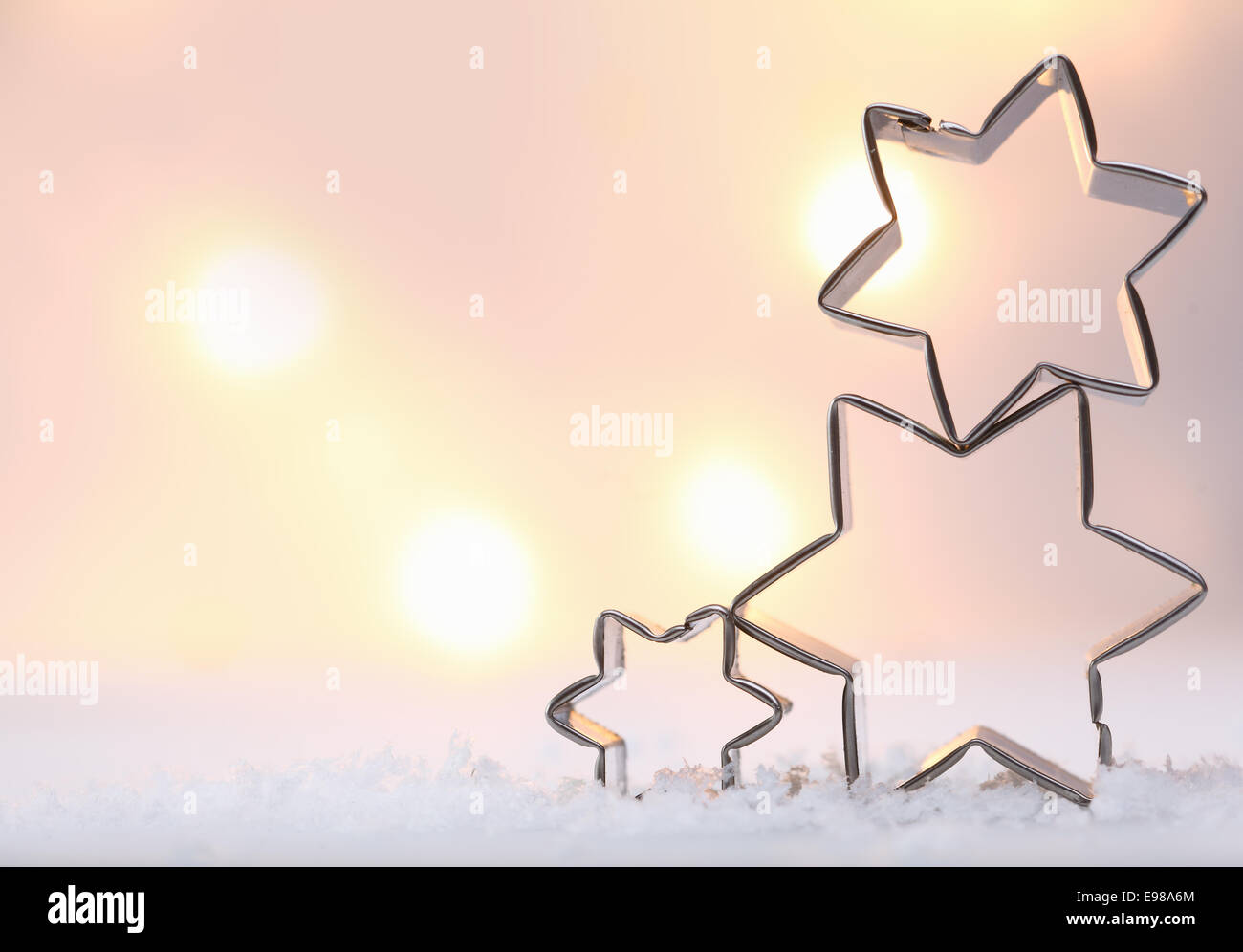 Stimmungsvolle Weihnachten Sterne Hintergrund mit drei Metall Sterne Ausstechformen übereinander auf Schnee gegen eine weiche ausgeglichen Stockfoto