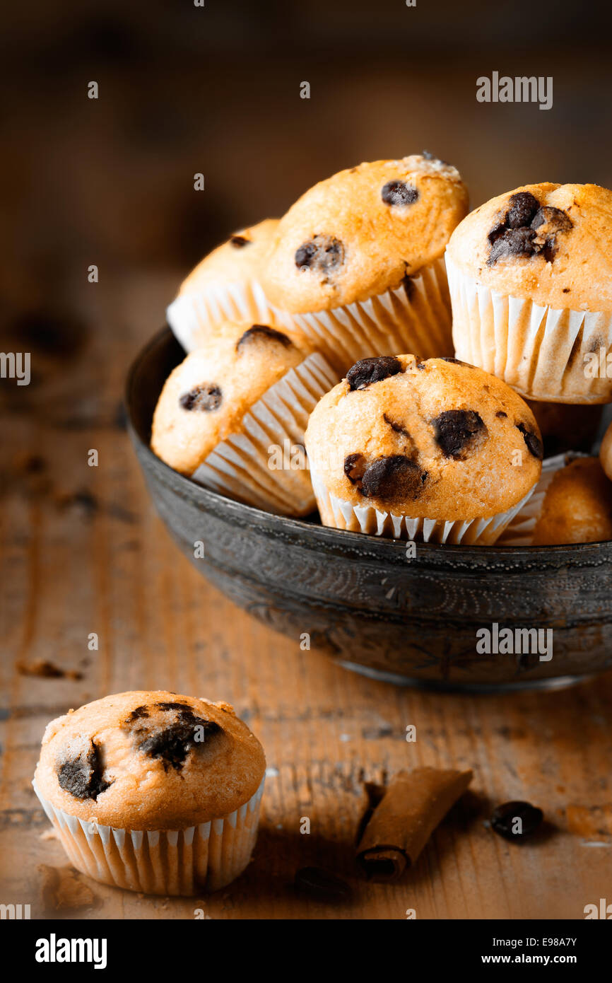 Ein einziges Mini-Muffin auf alter Holztisch mit einer weiteren Schüssel Muffins im Hintergrund Stockfoto