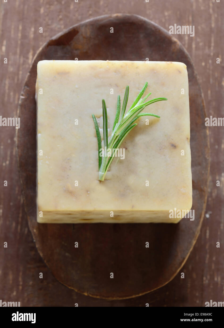 Frischen Rosmarinzweig auf ein Stück Seife ruht in einem alten rustikalen Holzschale, Draufsicht Stockfoto
