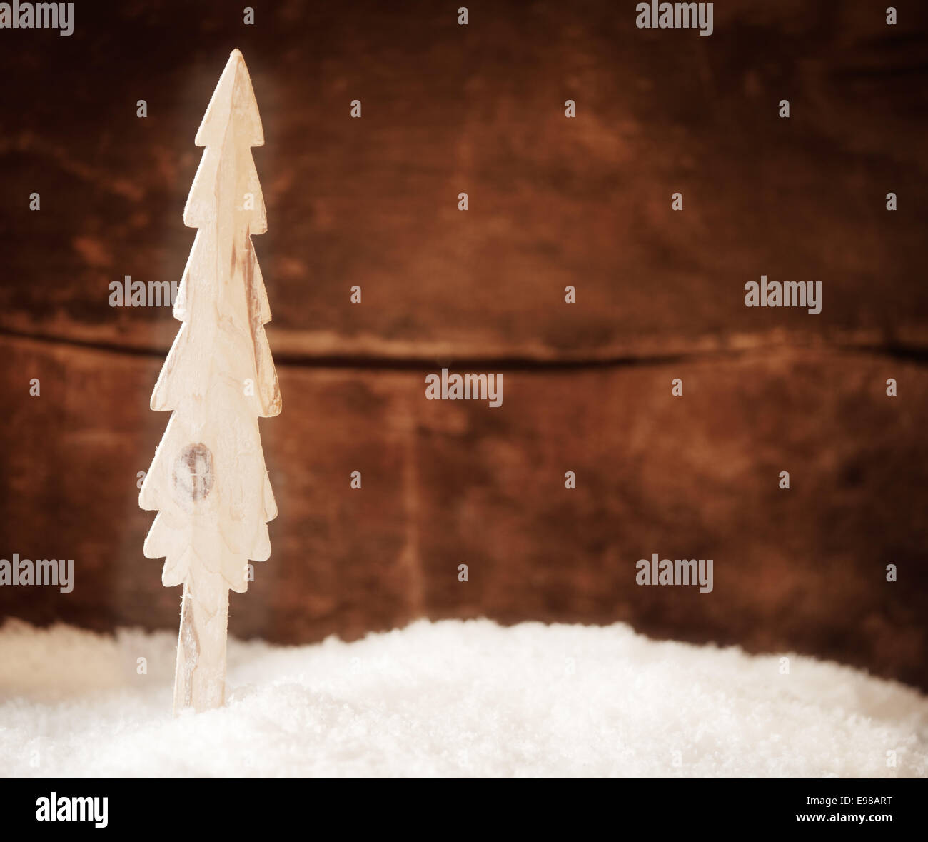 Stilisierte Holz Weihnachtsbaum stehen in frischen Winterschnee vor einer rustikalen Holzwand mit Exemplar für Ihre saisonalen Weihnachten Gruß oder Einladung Stockfoto
