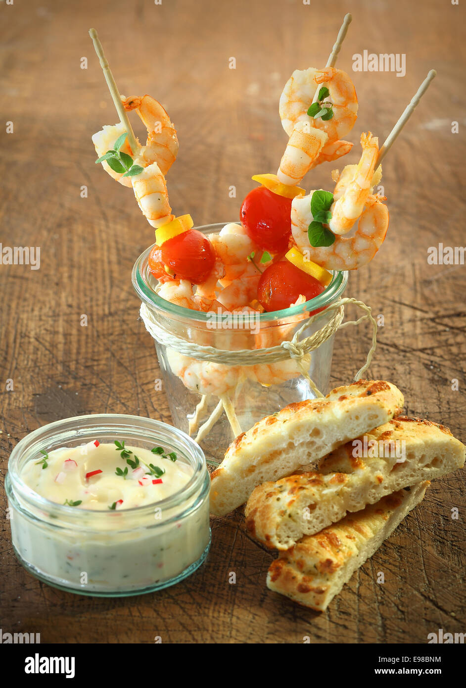 Leckere Vorspeisen, Fisch und Meeresfrüchte cocktail-sticks mit Shrimps, Käse und Tomaten stehen in einem Glas neben frische Focaccia Brot und eine Wanne mit Tartare sauce Stockfoto