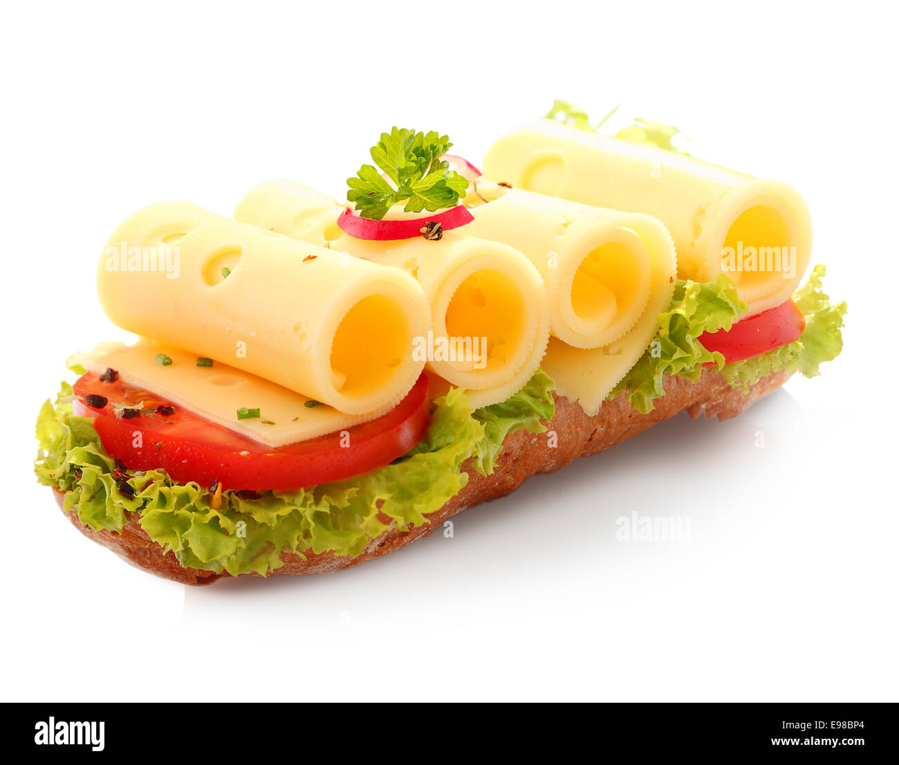 Dekorative offene Baguette-Sandwich mit vier Scheiben gerollte Käse auf frischem Salat und Tomatenscheiben rot auf weißem Hintergrund Stockfoto