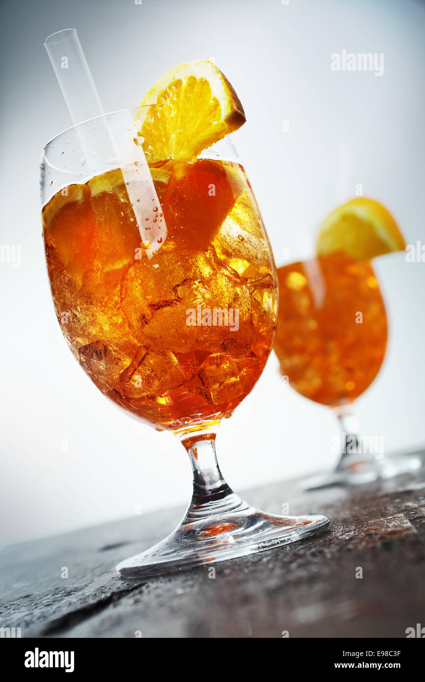 Goldene Orange und Rum cocktail Aperol Sprizz in lange Stielgläser auf eine alte hölzerne Theke, niedrige serviert Winkel schräge Ansicht Stockfoto