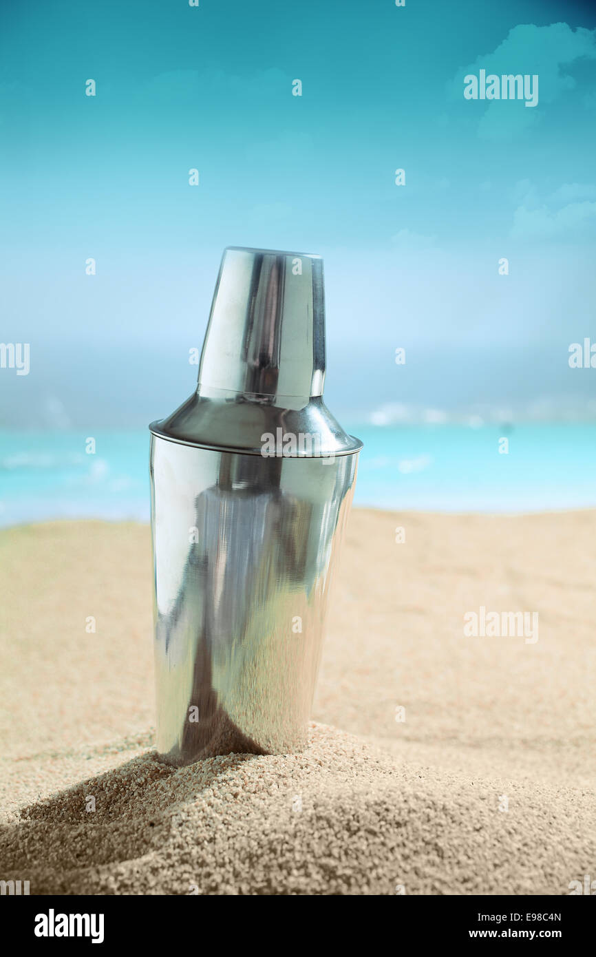 Moderne metallic Silber Martini cocktail-Shaker stehend auf dem goldenen Sand von einem tropischen Strand in der Sommersonne Stockfoto