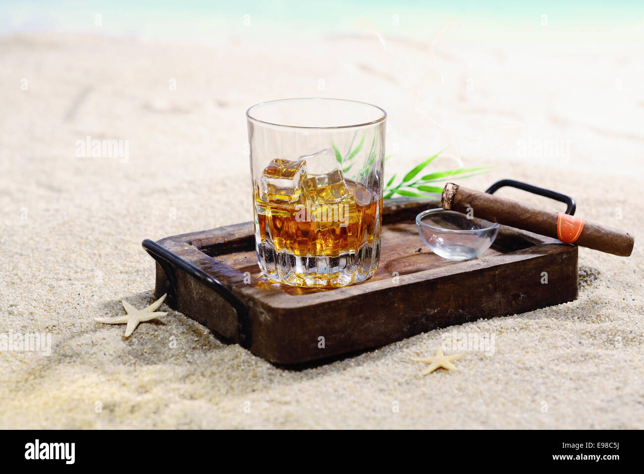 Schönes Bild von Scotch auf den Felsen in einen stilvollen Holztablett an einem Sandstrand. Stockfoto