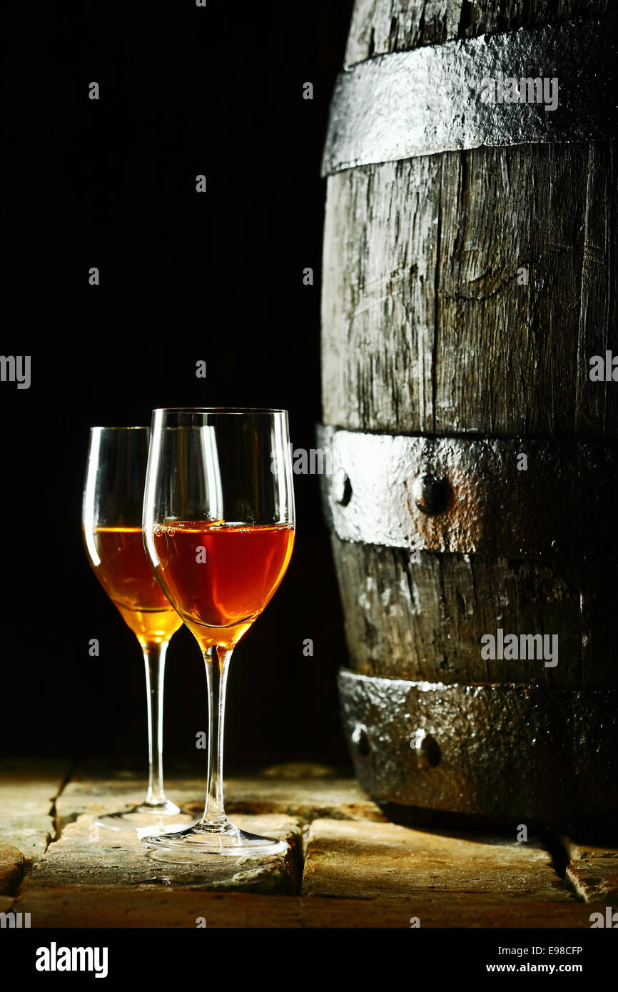 Alte Eiche Weinfass mit zwei Gläser Rotwein vor einem dunklen Hintergrund erinnert an einen Keller in einem Weingut Stockfoto