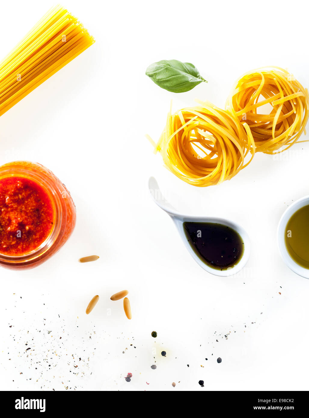 Verstreute frische Zutaten auf einem weißen Hintergrund für italienische Pasta mit Tomaten kochen-paste, Soja-Sauce, frischem Basilikum, Olivenöl und ungekochte Spaghetti und fettucini Stockfoto
