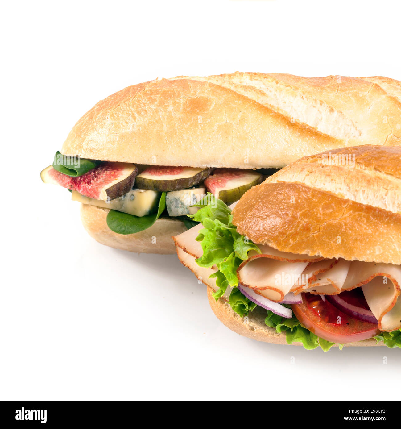 Zwei frische knusprige Baguettes mit herzhaften Füllung, mit in Scheiben geschnittenen Feigen, Spinat und Blauschimmelkäse und das andere mit geschnittenem Huhn und Salat auf weiß im quadratischen Format verarbeitet Stockfoto