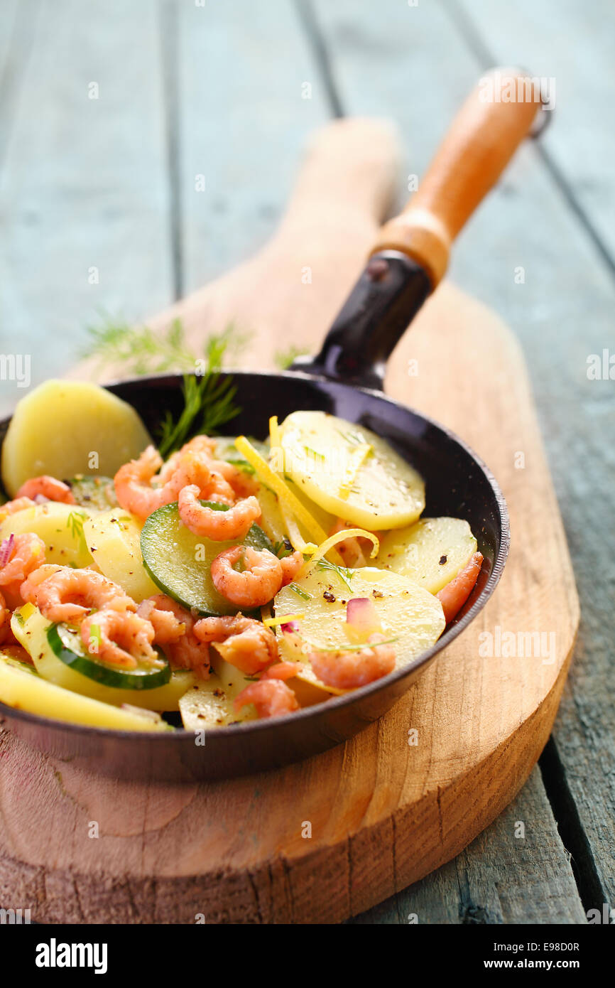 Garnelen, Zucchini und Kartoffel Pfanne gebraten und serviert in der Pfanne  auf einem Holzbrett für einen gesunden, frischen Fisch essen  Stockfotografie - Alamy