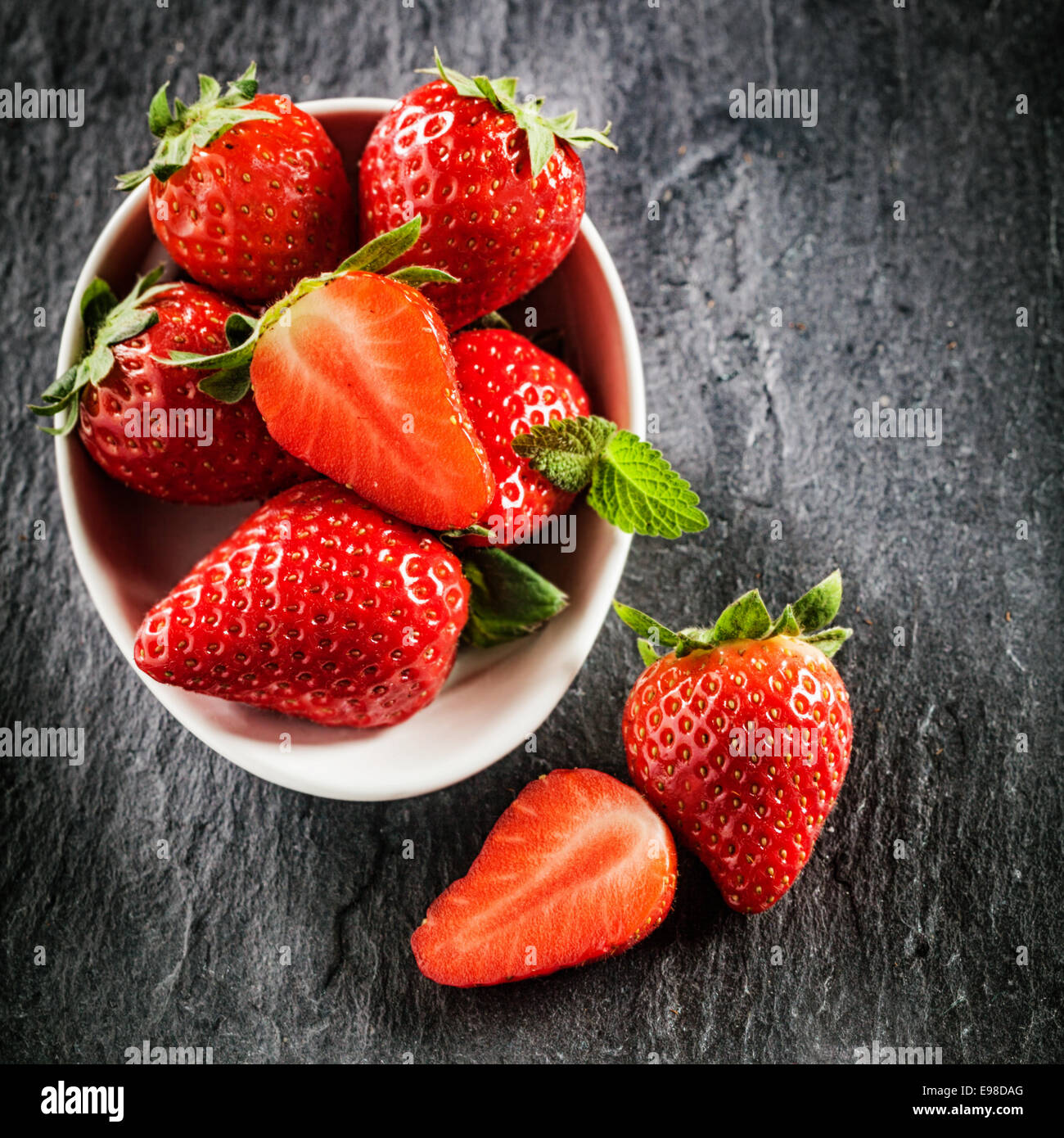 Frisches, neues Bild von Erdbeeren auf Schiefer Hintergrund im quadratischen Format mit Exemplar. Stockfoto