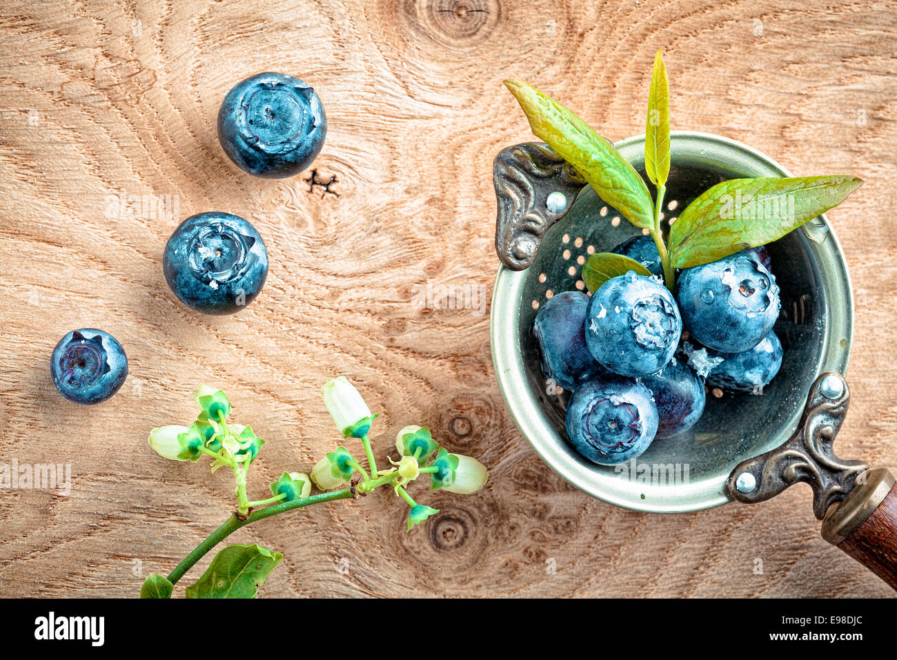 Draufsicht Heidelbeeren in eine alte antike Metall Pfanne dekoriert mit Blätter und Knospen blühen Stockfoto