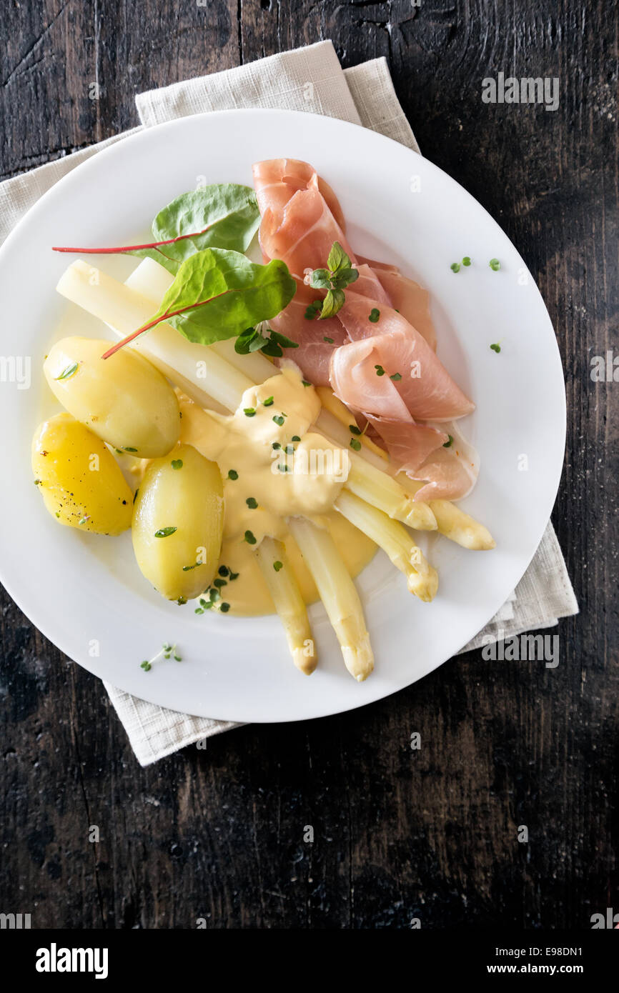 Ausschank von dünn geschnittenen Schinken, Spargel und Kartoffeln garniert mit Mayonnaise und frischen Kräutern, Draufsicht Stockfoto