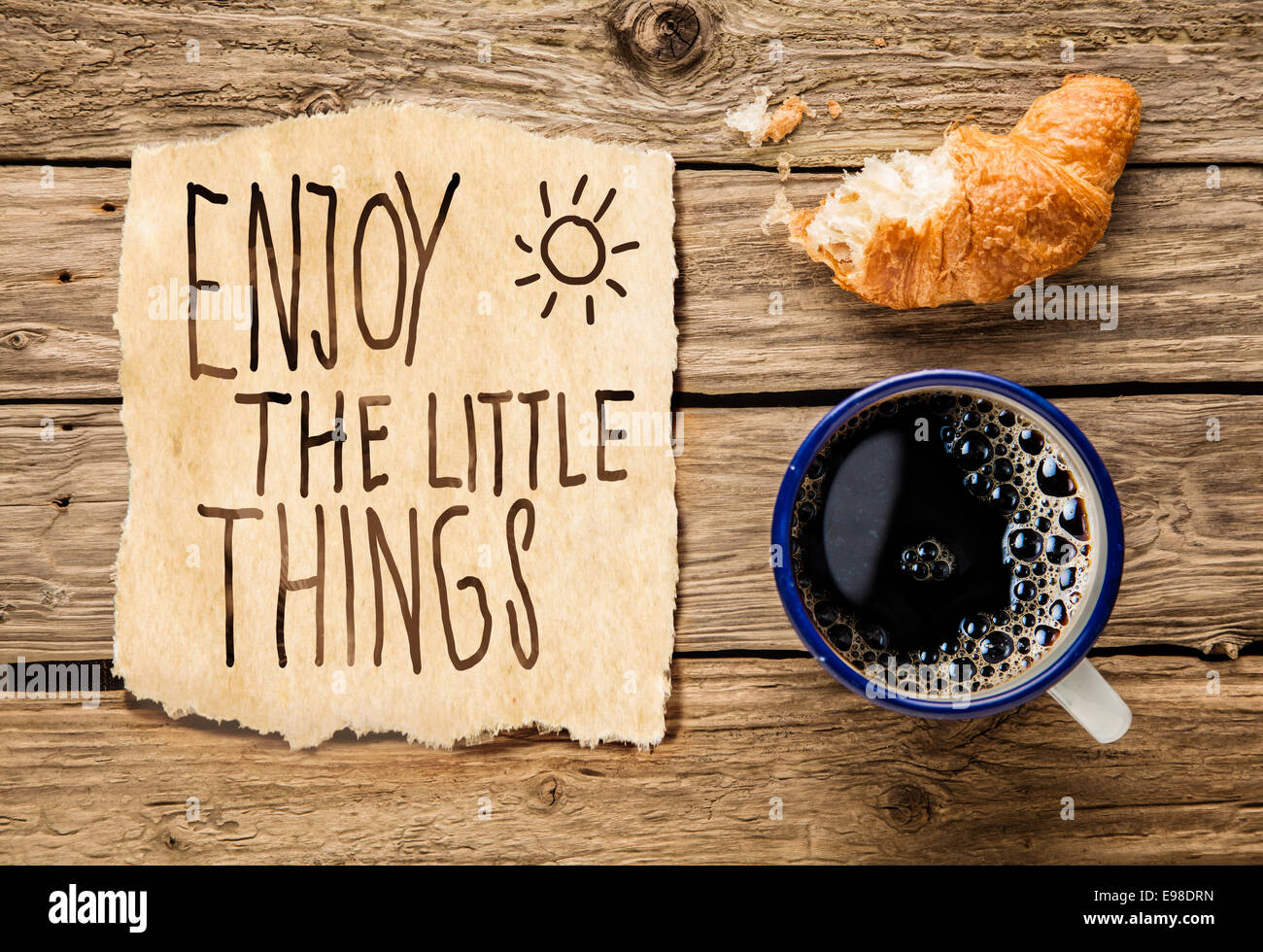Inspirierende früh morgens Frühstück mit eine halb gegessenen frischen Croissant mit Filterkaffee und eine handschriftliche Notiz - genießen die kleinen Dinge - erinnert uns auch die einfache Momente im Leben zu schätzen wissen Stockfoto
