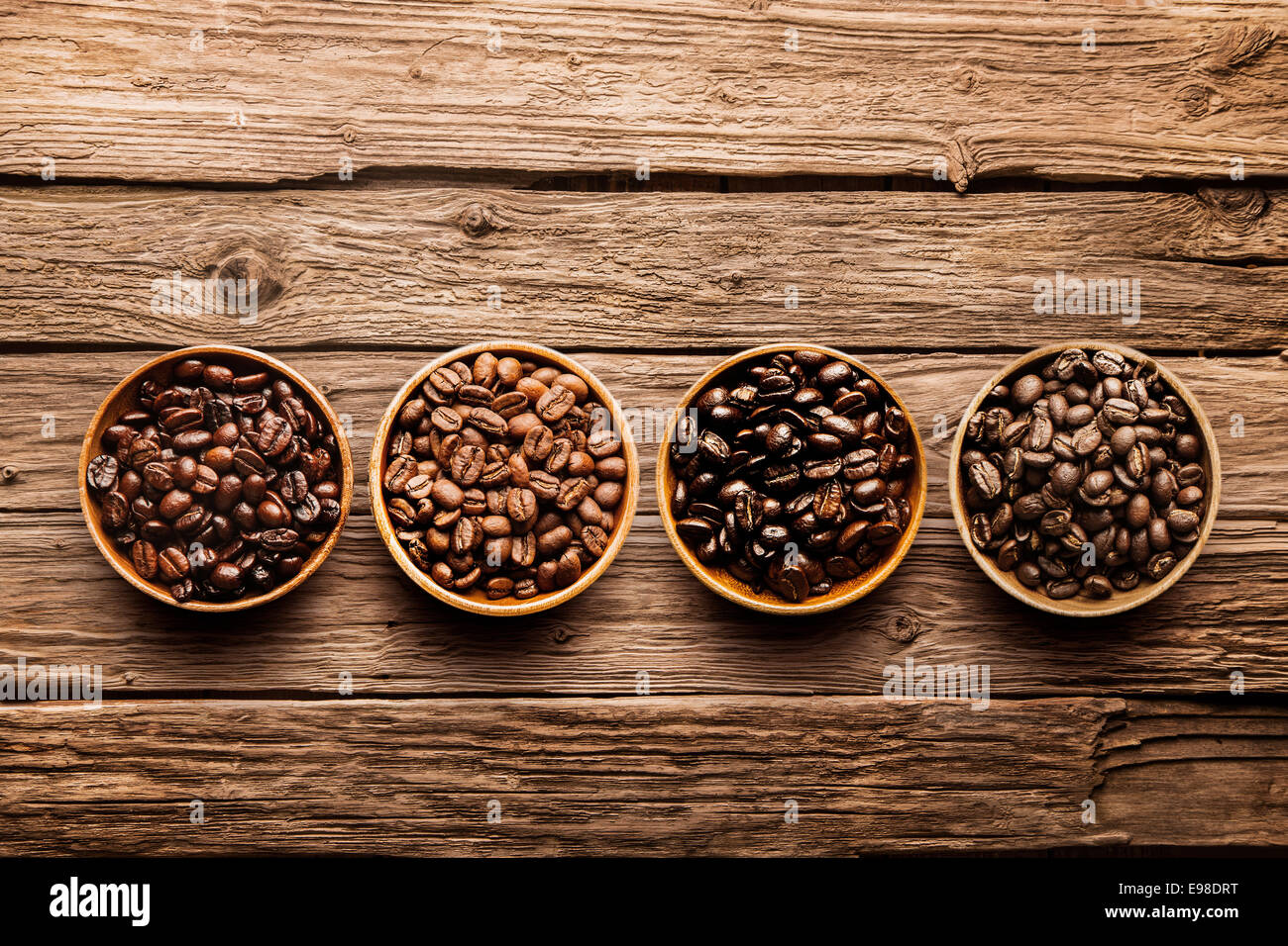 Verschiedene Rohe und geröstete Kaffeebohnen in kleinen Einzelbehältnissen auf einem rustikalen, verwitterte strukturierte Treibholz-Hintergrund, Draufsicht mit Exemplar Stockfoto