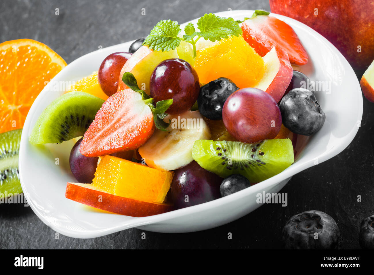 Bunte Schale mit gesunden tropischen Obstsalat mit Heidelbeeren, Erdbeeren, Kiwi, Banane, Traube, Orange für ein leckeres erfrischendes Frühstück Stockfoto