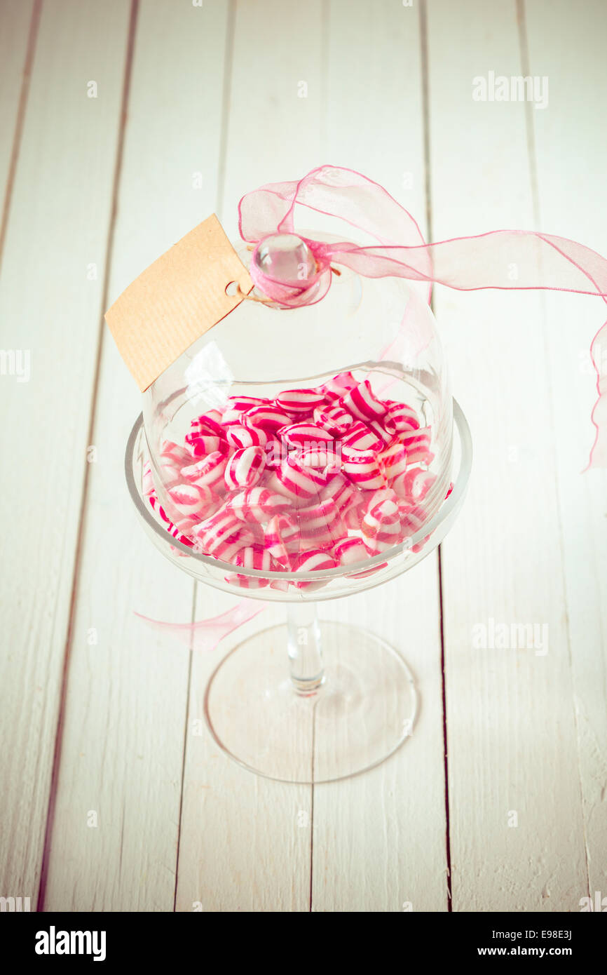Festliche rote und weiße Süßigkeiten in eine elegante klare Glasschale mit einer angehängten leer Geschenkanhänger für einen lieben Menschen Stockfoto