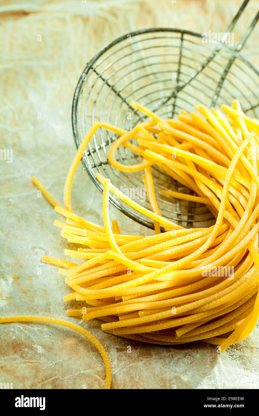 Retro-Draht-Sieb mit entwässert gekochte Spaghetti zu herzhaften Zutaten für ein köstliches italienisches Nudelgericht hinzugefügt werden Stockfoto