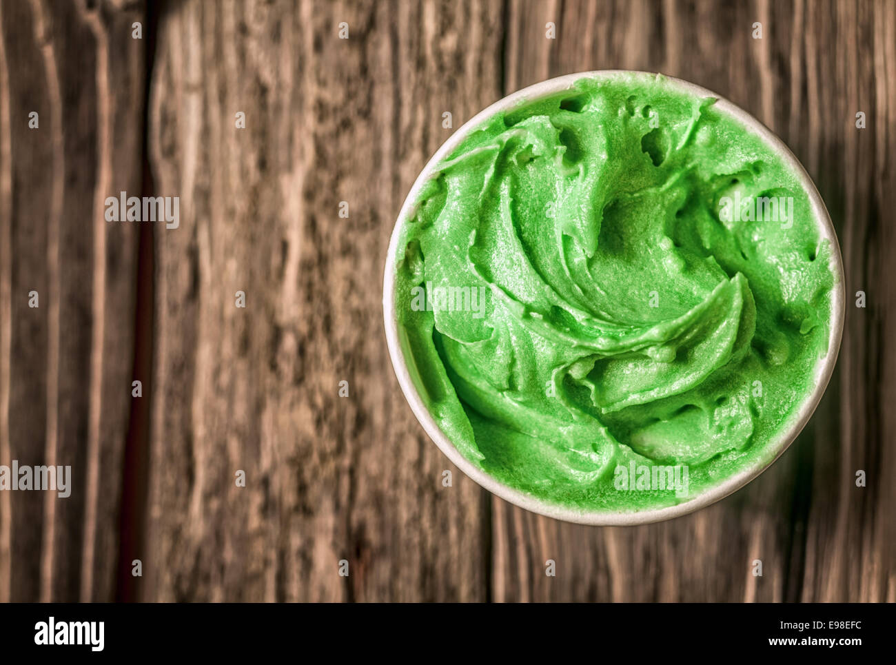 Appetitlich Wanne mit grünen italienisches Eis für eine erfrischende Köstlichkeit an einem Sommertag serviert auf einem alten hölzernen in der Lage mit Exemplar, Ansicht von oben Stockfoto