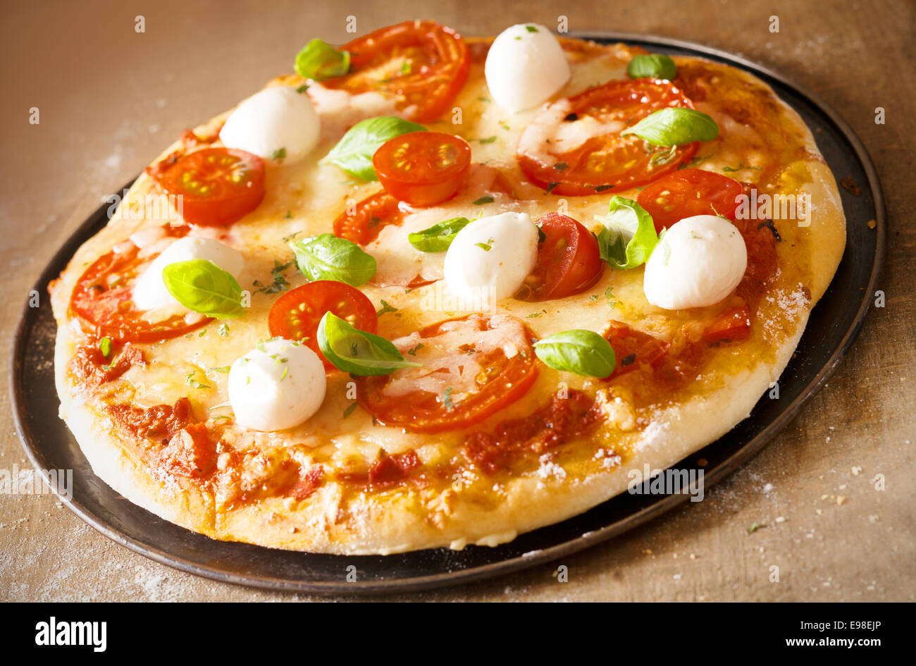 Frisch gebackene golden knusprige italienische Pizza mit Mozzarella, Tomaten und Basilikum auf geschmolzenem Käse und Tomaten paste Stockfoto