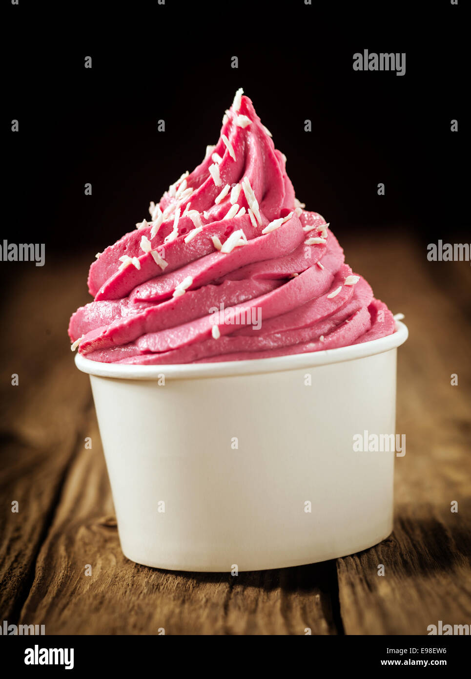 Strudel von köstlichen Beeren-Eis oder gefrorenen Joghurt in einer Kunststoffwanne zum Mitnehmen mit Dehydriertes Coconut gegen einen dunklen bestreut Stockfoto