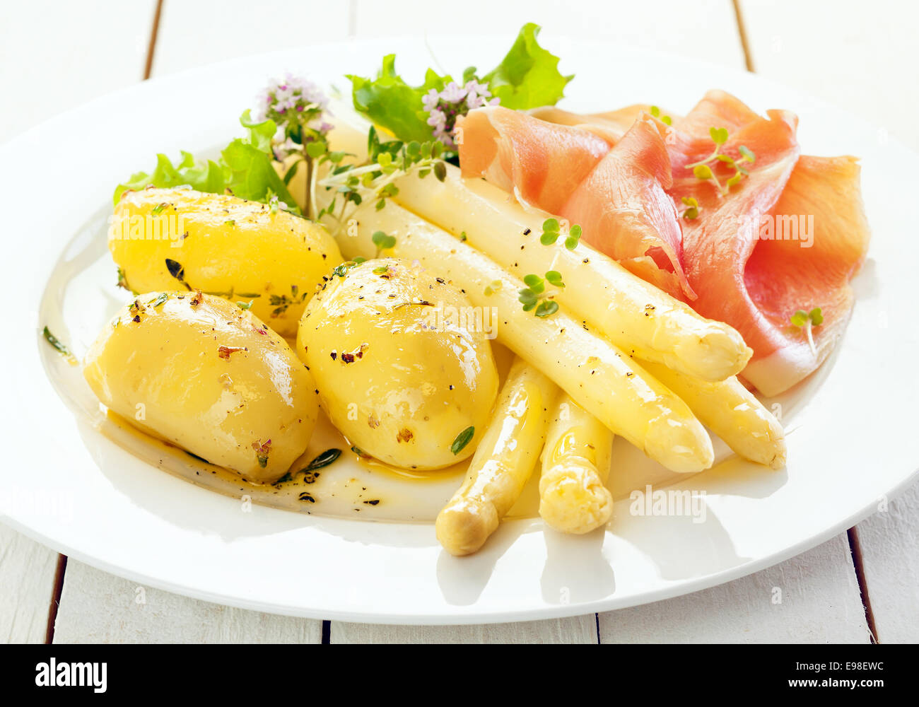 Kalter Spargel mit Parmaschinken und gekochtem Babykartoffeln serviert mit Salat und gehackte frische Kräuter, Nahaufnahme auf einer Platte Stockfoto