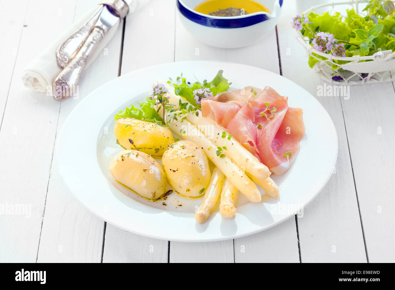 Köstliche kalte Sommer Mittagessen mit Prosciutto Schinken mit Spargel und baby-Kartoffeln garniert mit gehackten Kräutern auf einem weißen Land Küchentisch mit einer Schüssel Koriander Stockfoto