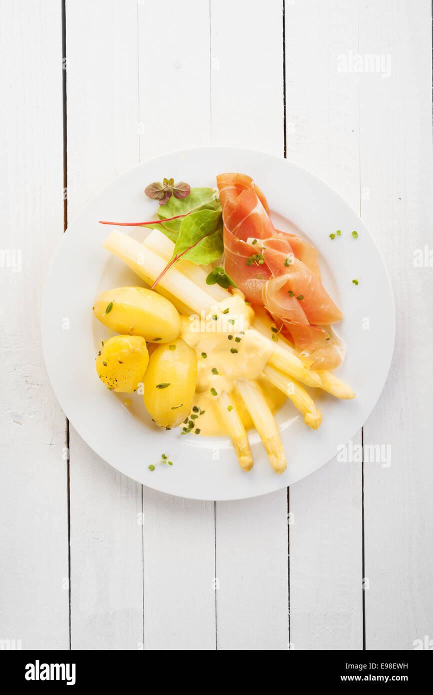 Spargel und italienischen Parma oder Prosciutto-Schinken mit Mayonnaise serviert mit Baby gekochte Kartoffeln für ein köstliches kalter Sommer essen, Draufsicht auf weißer Holztisch mit Exemplar Stockfoto