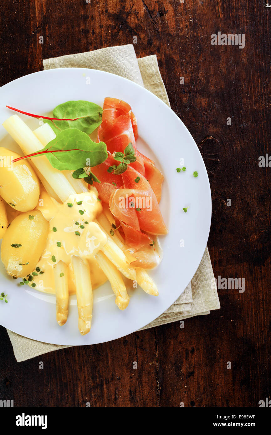 Köstliche kalte Sommer Abendessen mit Parmaschinken und weißen Spargelspitzen garniert mit würzigen Mayo, serviert mit gekochten Babykartoffeln Aufwand anzeigen auf einem dunklen Hintergrund Stockfoto