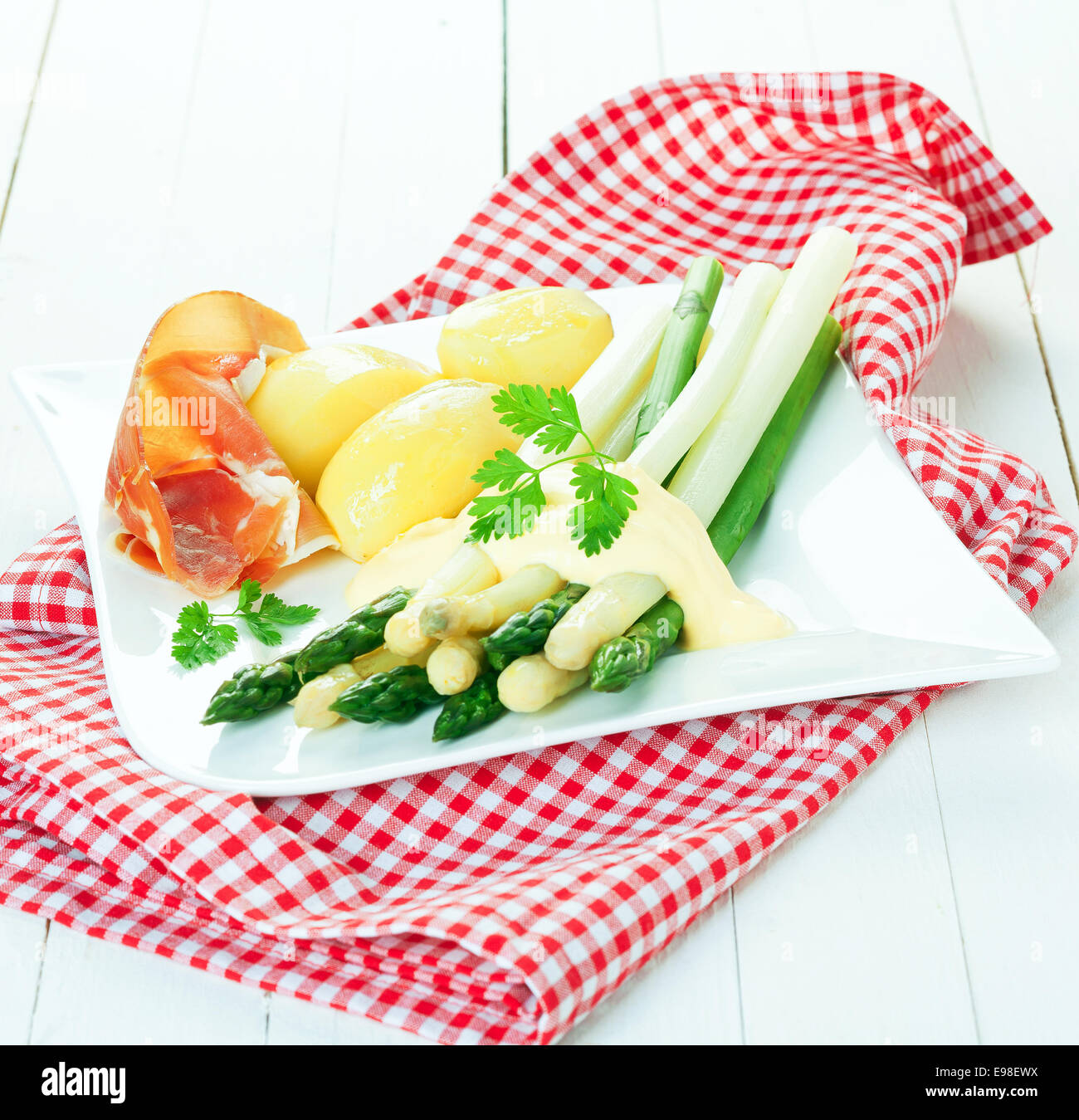 Landhausküche mit Gourmet-Schinken Schinken und grünen und weißen Spargelspitzen mit Kartoffeln und Mayo auf einem modernen Teller serviert auf einem roten und weißen aufgegebenes Tuch Stockfoto