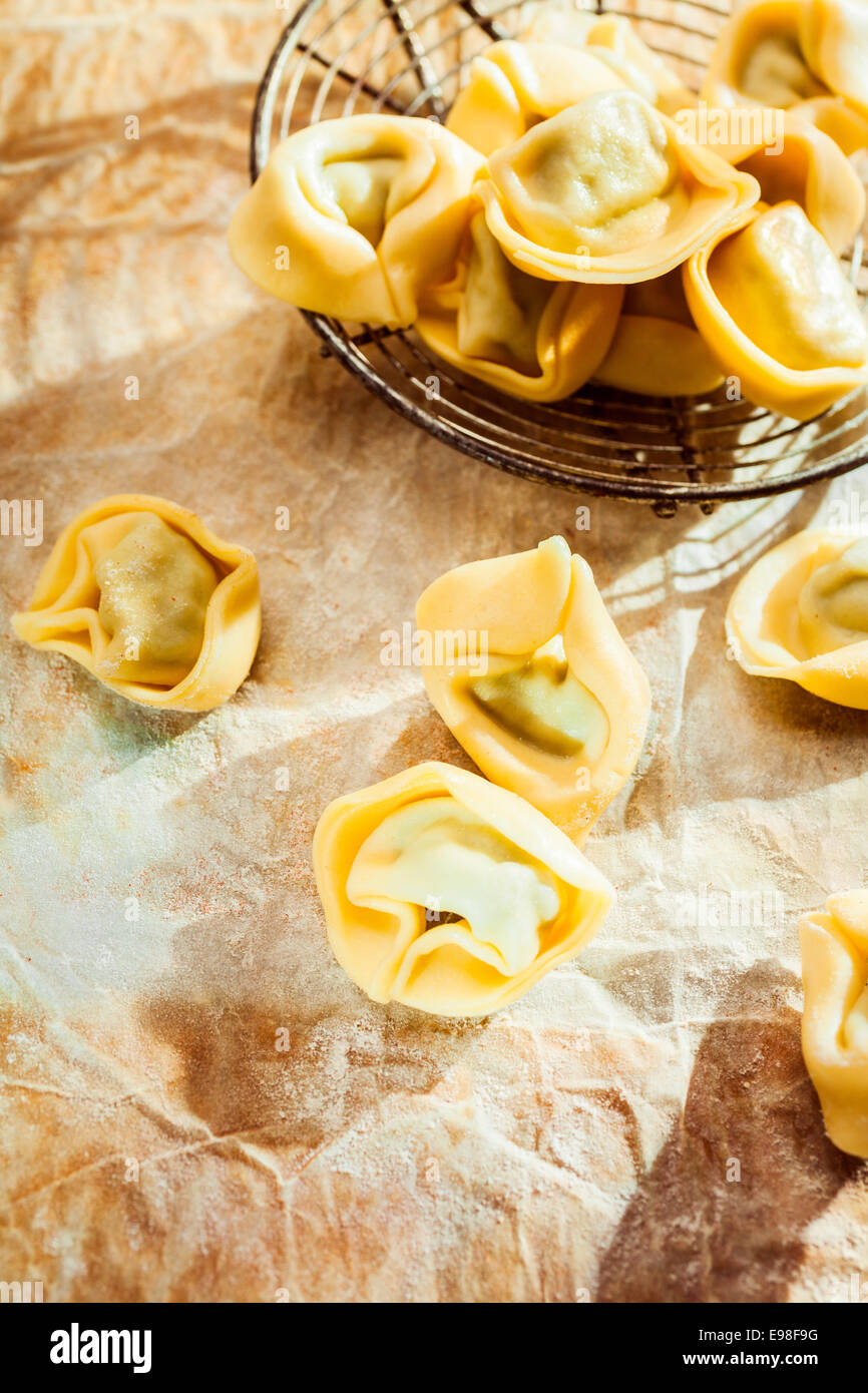 Ungekocht herzhafte italienische Tortellini ringförmige Nudeln für traditionelle mediterrane Küche auf zerknittertes Papier auf einem Küchentisch, erhöhte Ansicht mit Exemplar Stockfoto