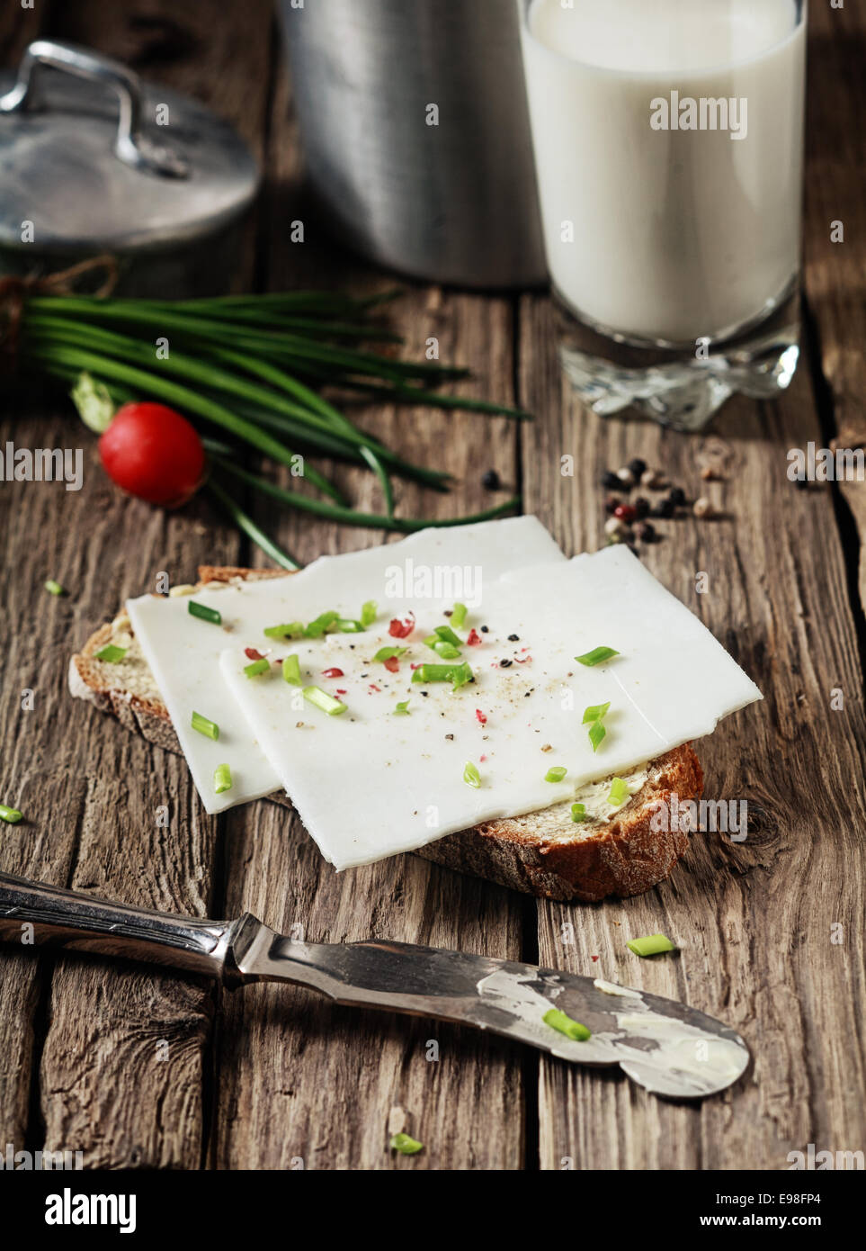 Einen köstlich Ziegen-Milch-Käse-Sandwich, garniert mit gehackten frischen sortierte Kräuter auf einer Scheibe Schwarzbrot in einer rustikalen Küche vorbereiten Stockfoto