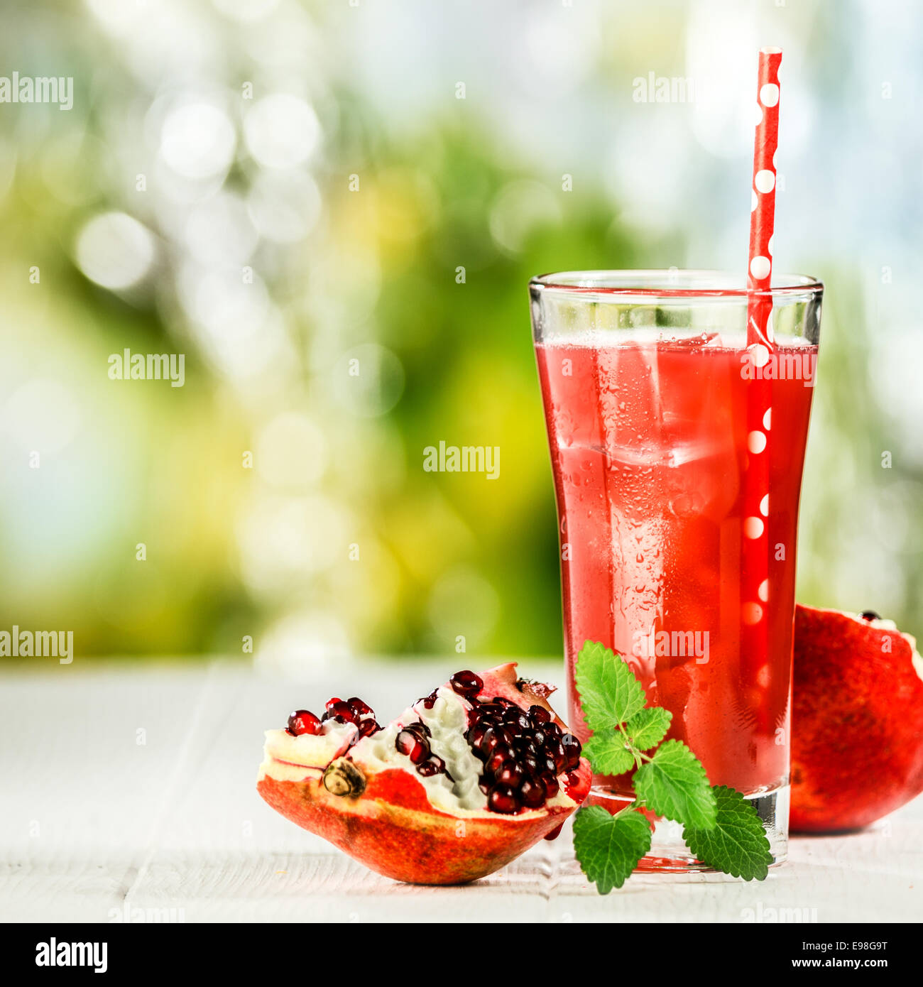 Granatapfel und Pfefferminze Fruchtsaft mischen mit frischen Zutaten stehen auf einem Tisch Picknick im Freien an einem sonnigen Sommertag, Seitenansicht Stockfoto