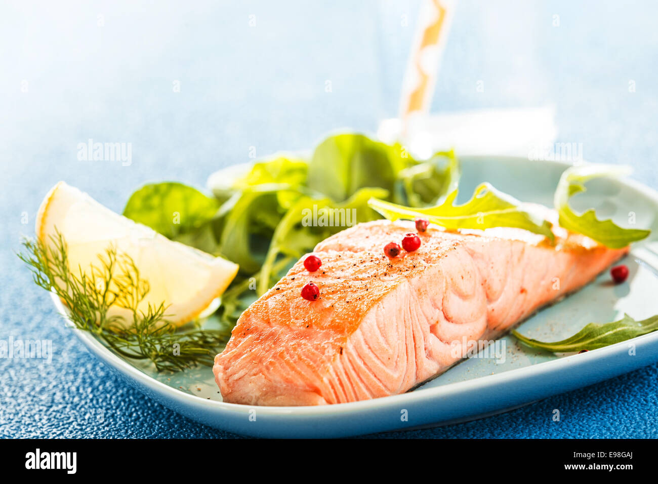 Köstlich saftige Portion gegrillter oder gebackener Frisches Lachsfilet serviert mit einem grünen Salat und Zitronenscheibe für Stockfoto