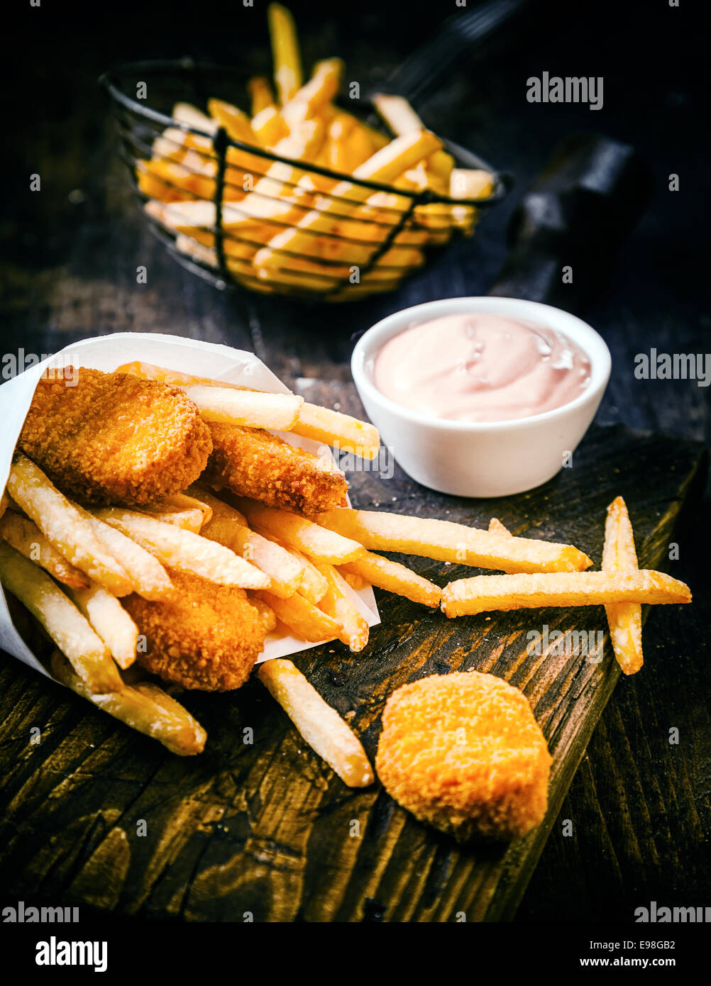 Knusprig goldene frittiertem Fisch und Kartoffel-Chips oder Pommes frites serviert mit einer pikanten Mayonnaise Dip auf einem alten Holztisch in ein Fischgeschäft Stockfoto