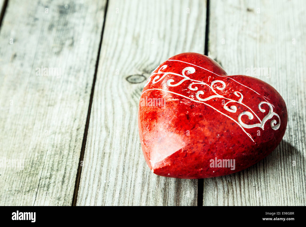 Rotes Herz geformten Stein auf Holzuntergrund Stockfoto