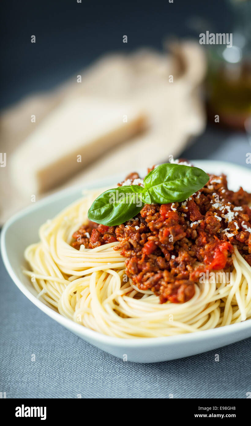 Traditionelle italienische Spaghetti gerieben garniert mit Bolognese mit Parmesan bestreut auf eine Tomate nach Fleisch-Sauce mit Basilikum garniert Stockfoto