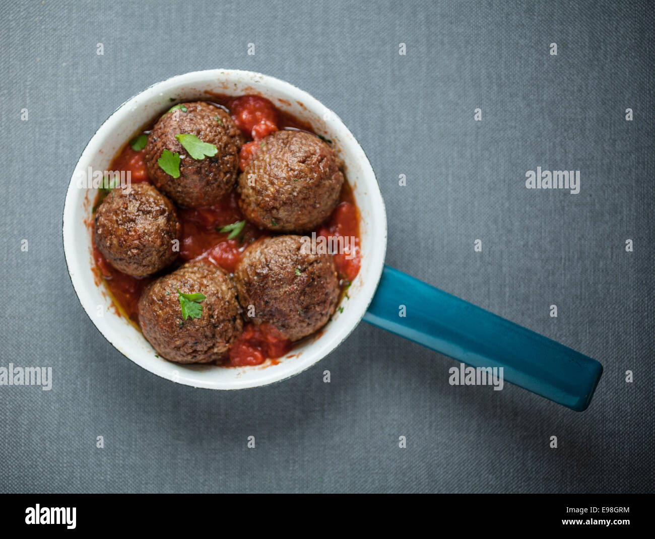 Lecker gewürzte Fleischbällchen in einem Topf mit einer pikanten Chilischote und Tomatensauce und frischen Kräutern, Draufsicht Stockfoto