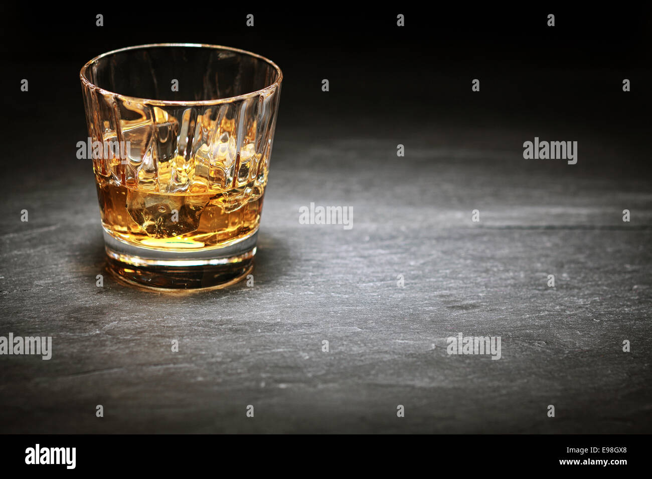 Whisky auf Eis in einem Glas Becher steht auf einem Zähler in den Schatten mit einem Highlight über Exemplar oder ein Ort für Stockfoto